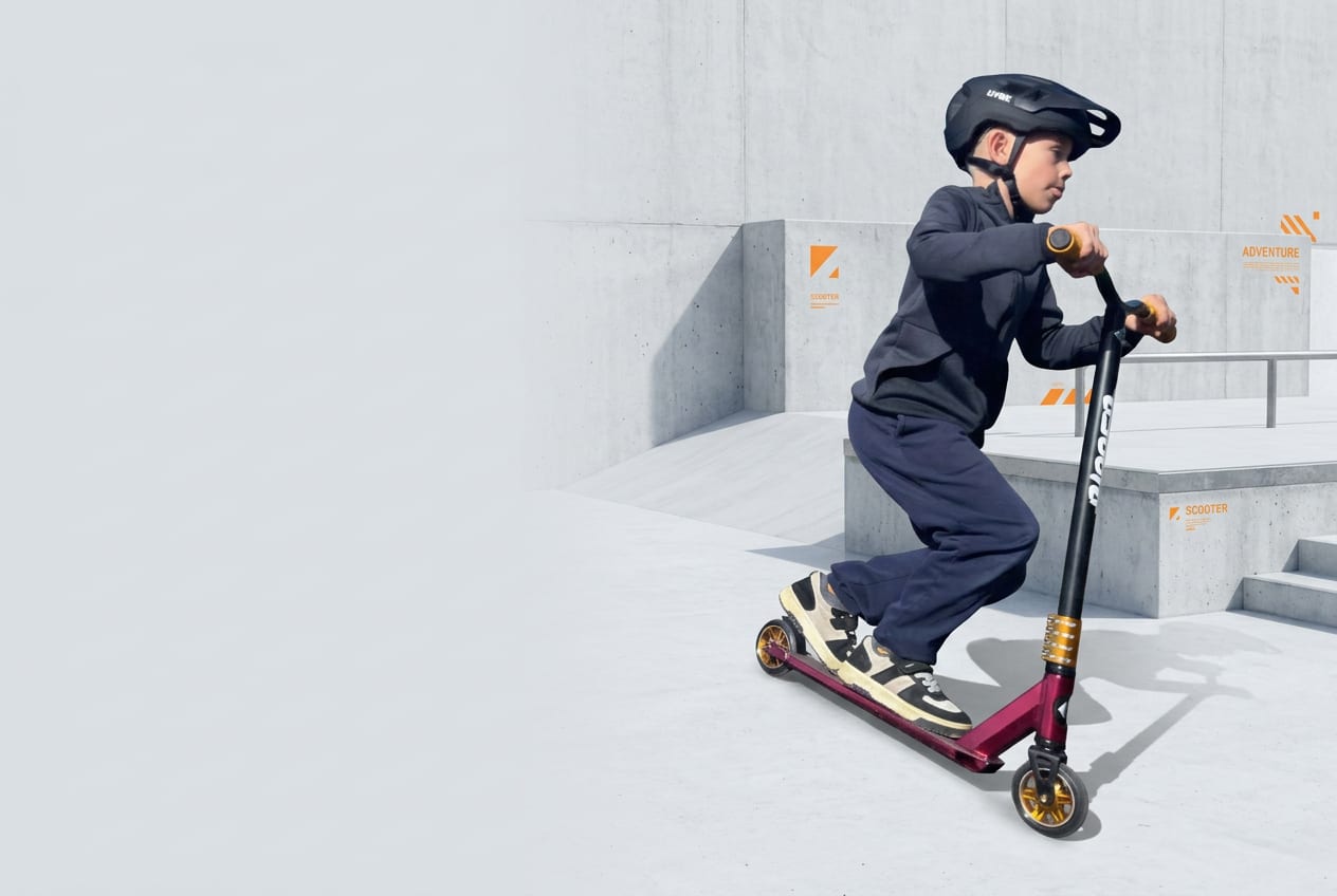 Richard v helmě jede na freestyle koloběžce ve skateparku